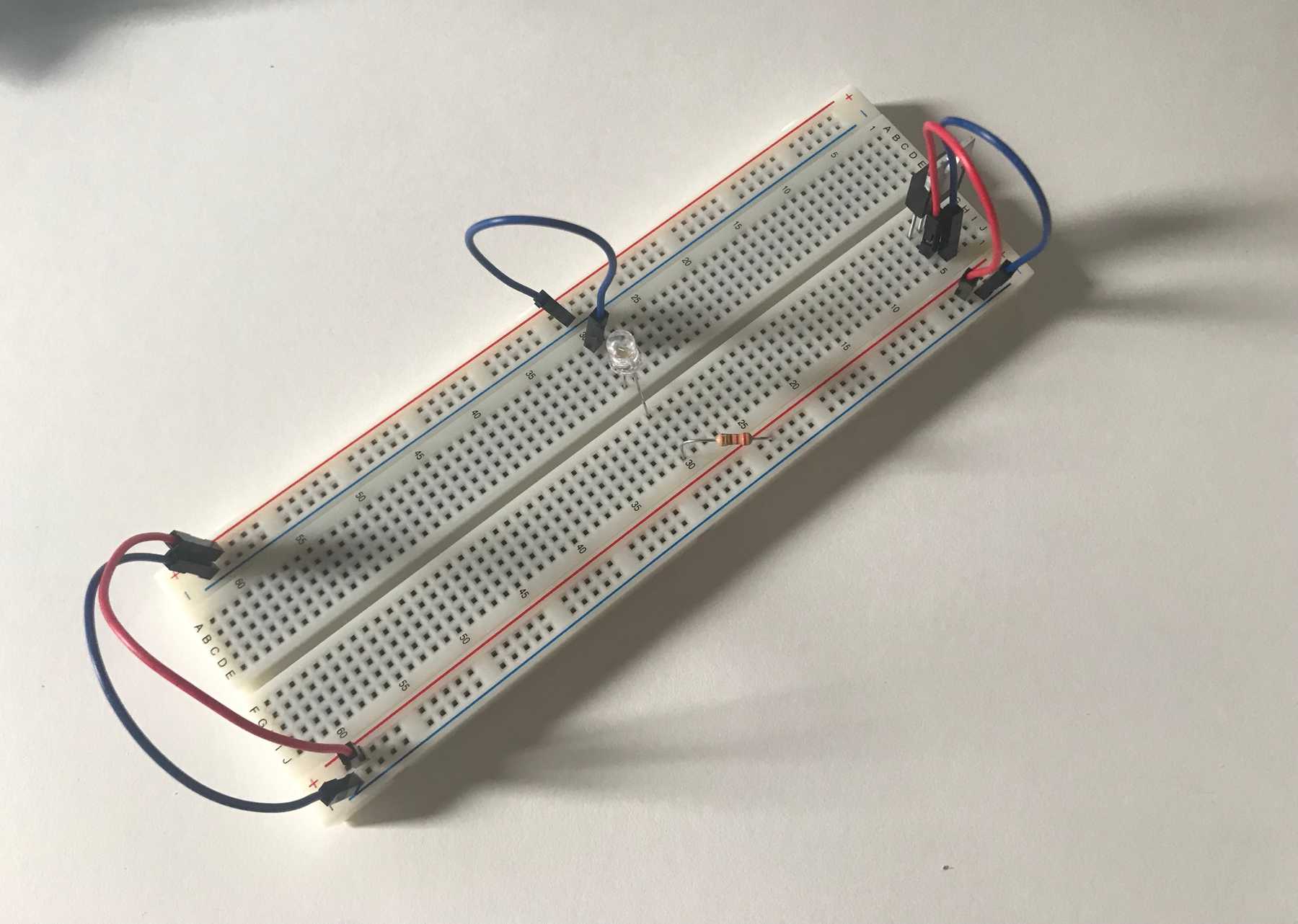 Breadboard with a resistor and LED in series connecting Vin to Ground